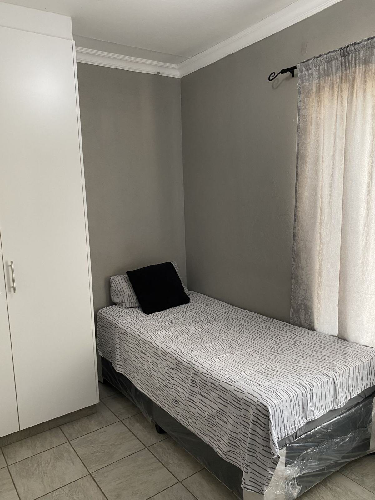 Bedroom with single bed, wardrobe and curtains